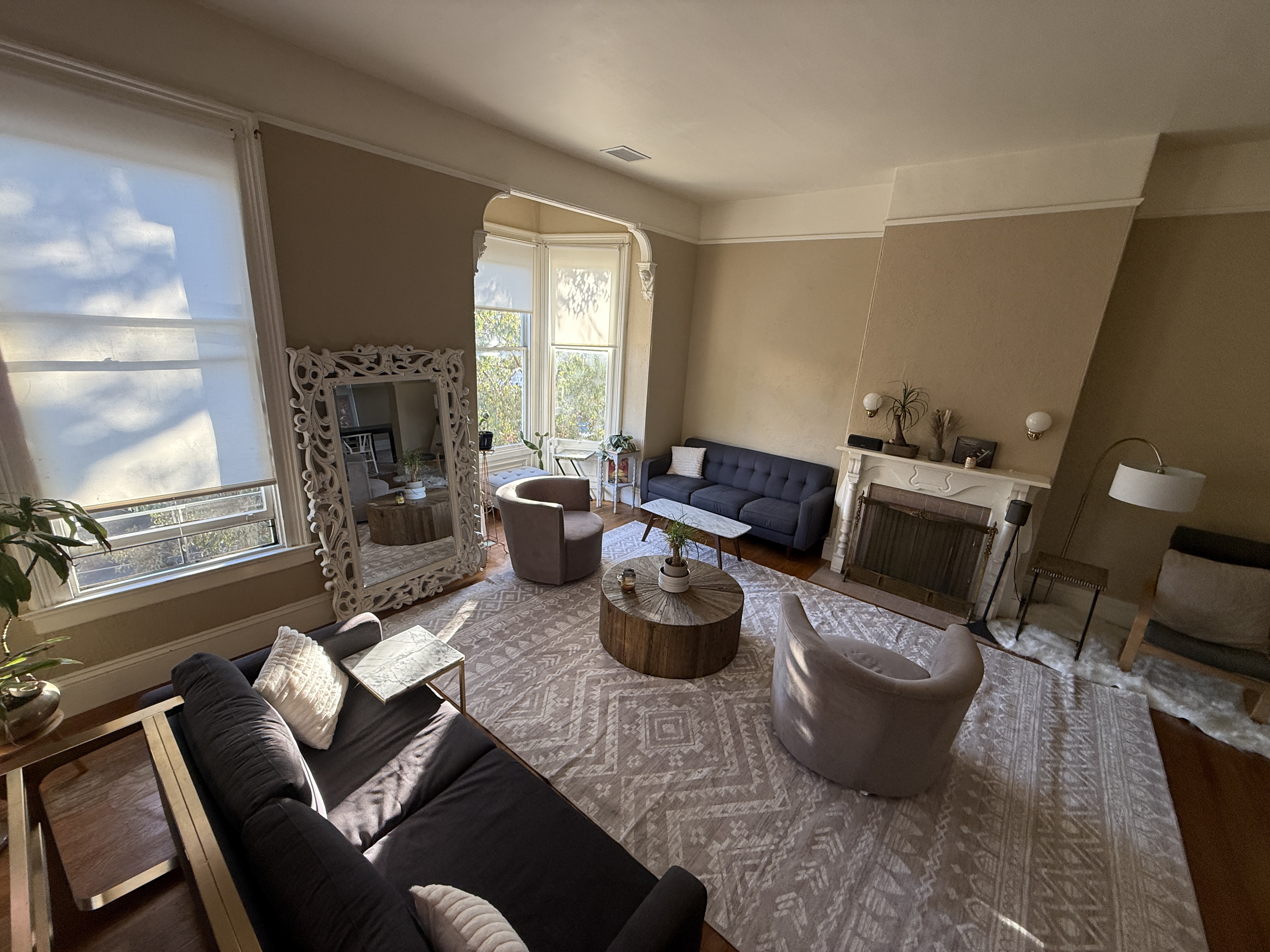 Living room with ornate white mirror, blue couch, and bay windows