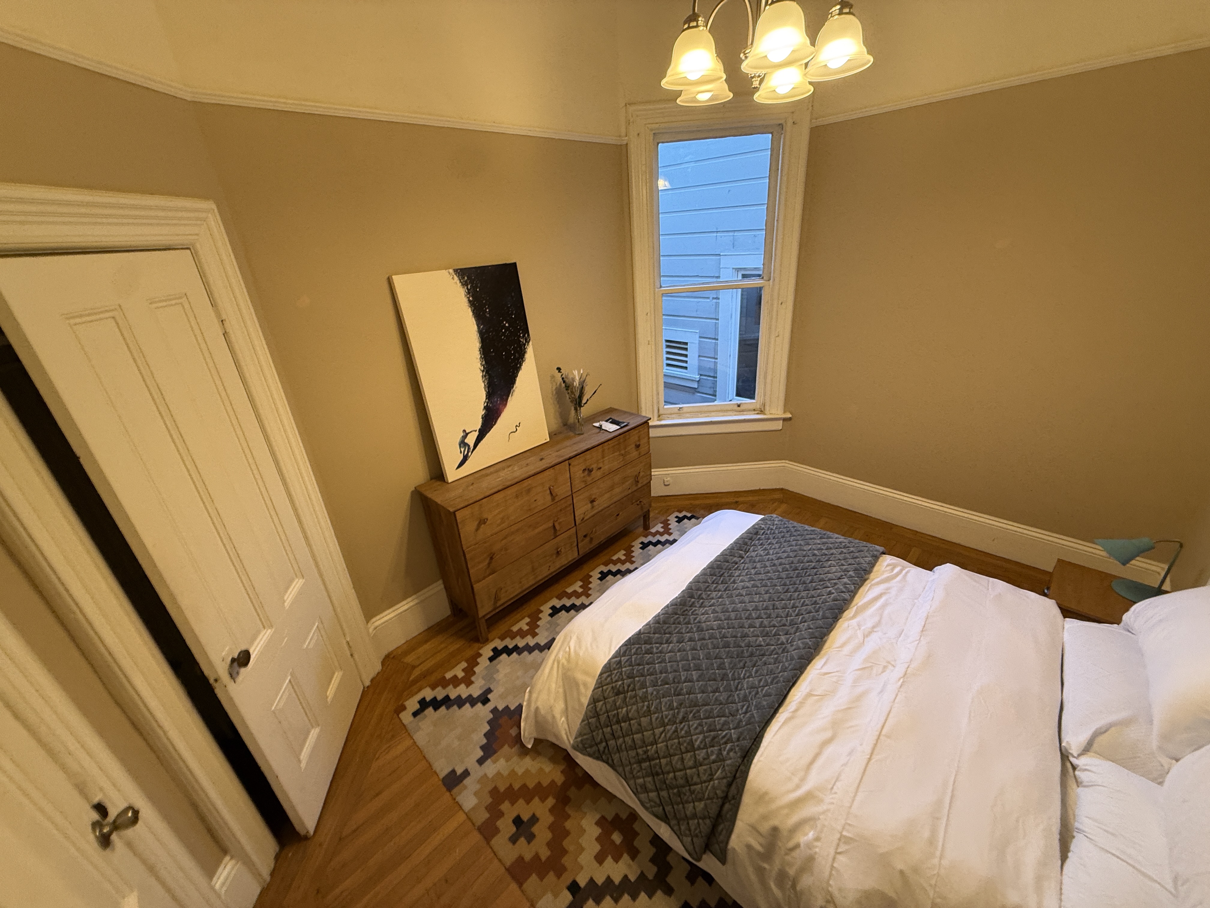 Bedroom with abstract art and wooden dresser