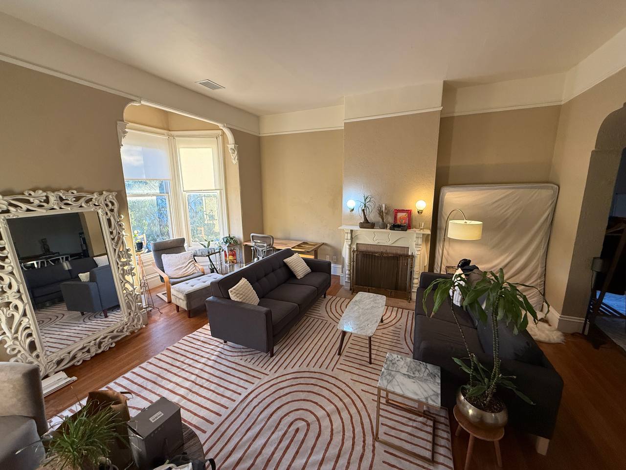 Living room with ornate white mirror, blue couches, striped rug and fireplace