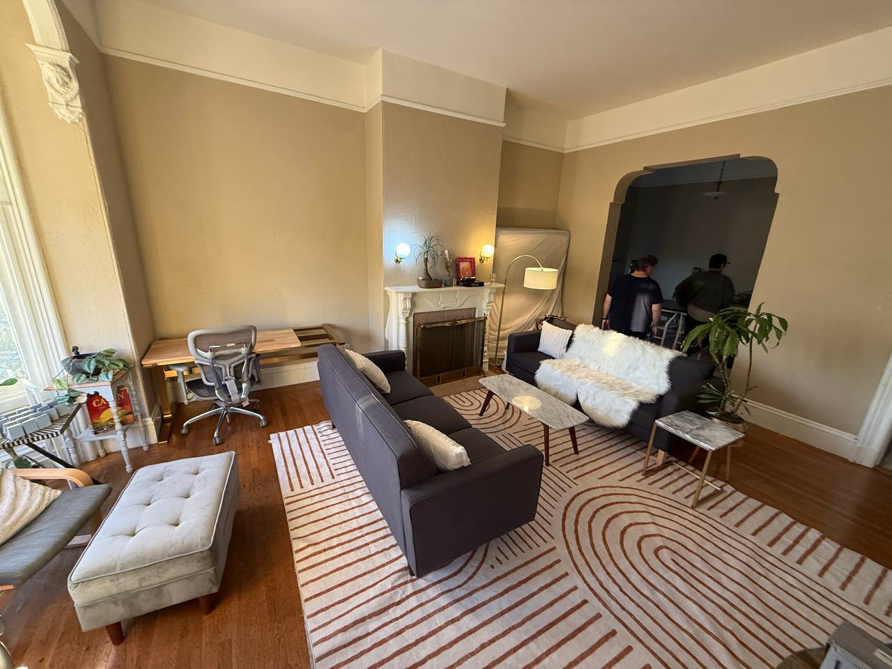 Living room with workspace desk, tufted ottoman and striped rug