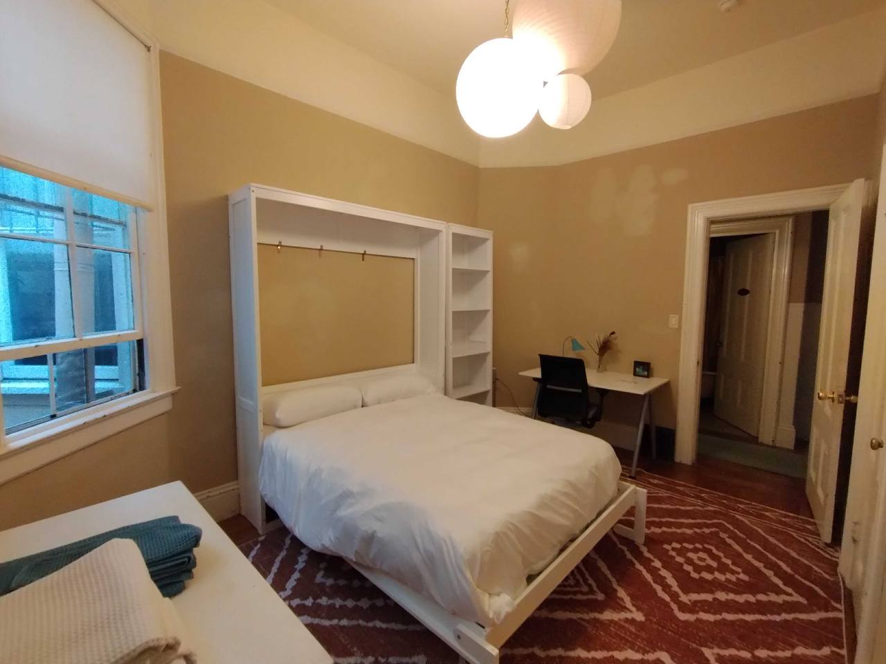 Murphy bed room with built-in white shelving and desk