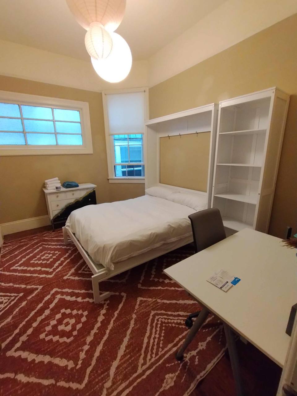 Murphy bed room showing white dresser and paper lanterns